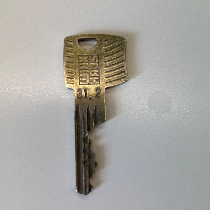 Ein alter Messingschlüssel mit der Nummer 31.2, auf einer weißen Oberfläche positioniert.