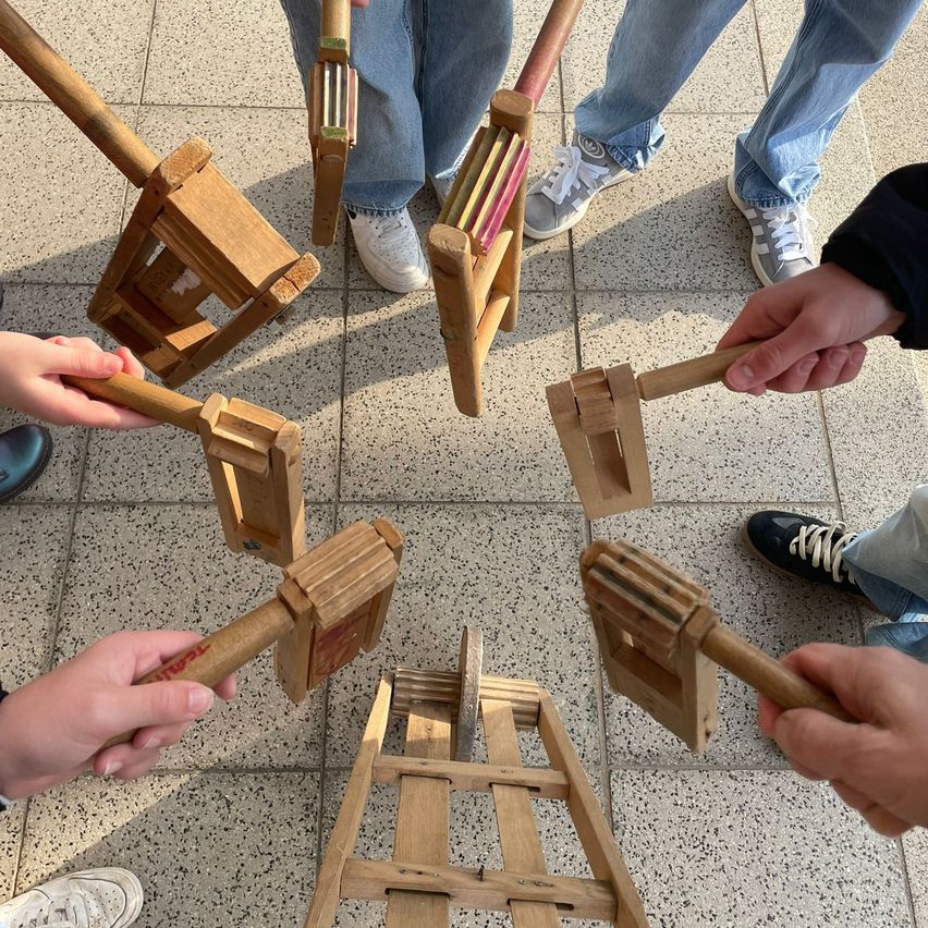 Eine Gruppe von Menschen steht im Kreis und hält Holzinstrumente. Sie scheinen sich auf eine musikalische Aufführung vorzubereiten.