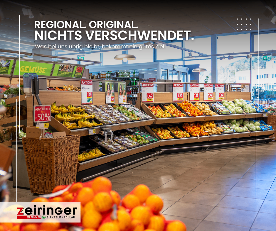A supermarket aisle with a variety of fruits and vegetables on display. The shelves are filled with bananas, apples, oranges, and other produce. A sign on the left indicates a 50% discount on apples. The store's slogan 'Regional. Original. Nothing Altered.' is displayed prominently.