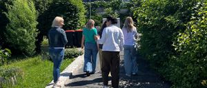 Eine Gruppe von Frauen geht auf einem von Grünpflanzen umgebenen Pfad. Das Wetter ist sonnig mit klarem blauem Himmel.