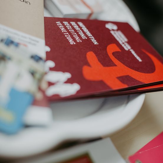 Ein Stapel roter Broschüren mit dem Wort Information und einem roten Logo mit dem Buchstaben F auf einem weißen Teller.