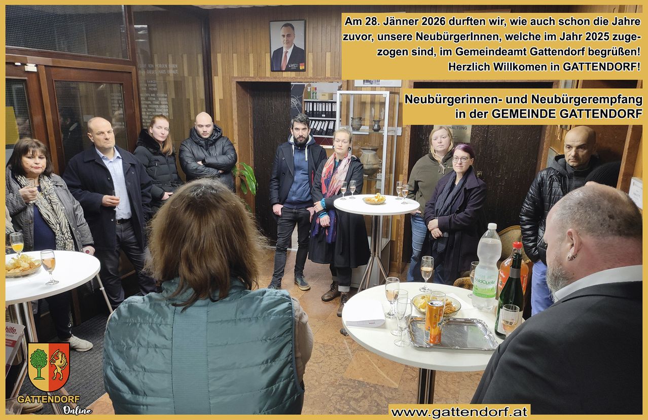 Eine Gruppe von Menschen steht in einem Raum, wahrscheinlich bei einer Willkommensveranstaltung. Ein Tisch mit Weingläsern, Snacks und Flaschen steht in der Mitte. Ein Plakat an der Wand lautet: 'Am 28. Jänner 2026 durften wir, wie zuvor, unsere Neubürgerinnen, welche ziehen sind, im Gemeindeamt Herzlich Willkommen.'