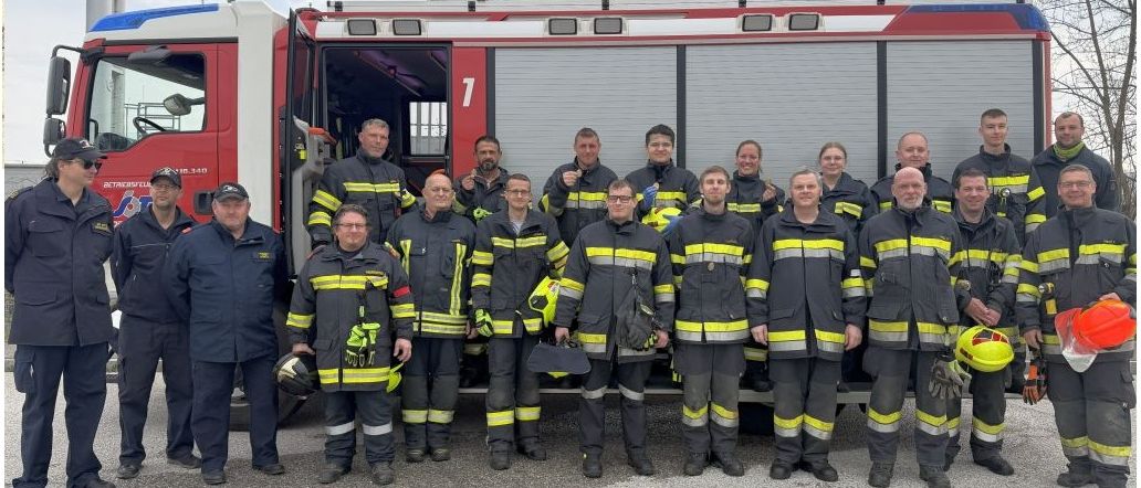 Zwei Bilder von Feuerwehrleuten und Freiwilligen, eines in Uniform und eines in formeller Kleidung, stehen zusammen vor einem Feuerwehrauto und einem Gebäude.