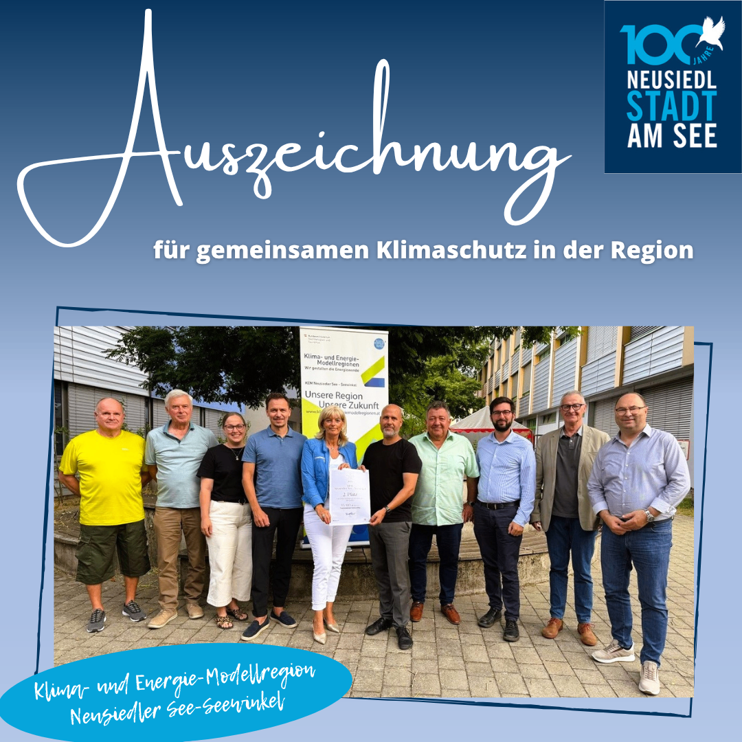 Eine Gruppe von Menschen steht vor einem Gebäude mit einem blauen Hintergrund und Text, der 'Auszeichnung für gemeinsamen Klimaschutz in der Region' lautet. Sie alle lächeln und scheinen für ein Foto zu posieren.