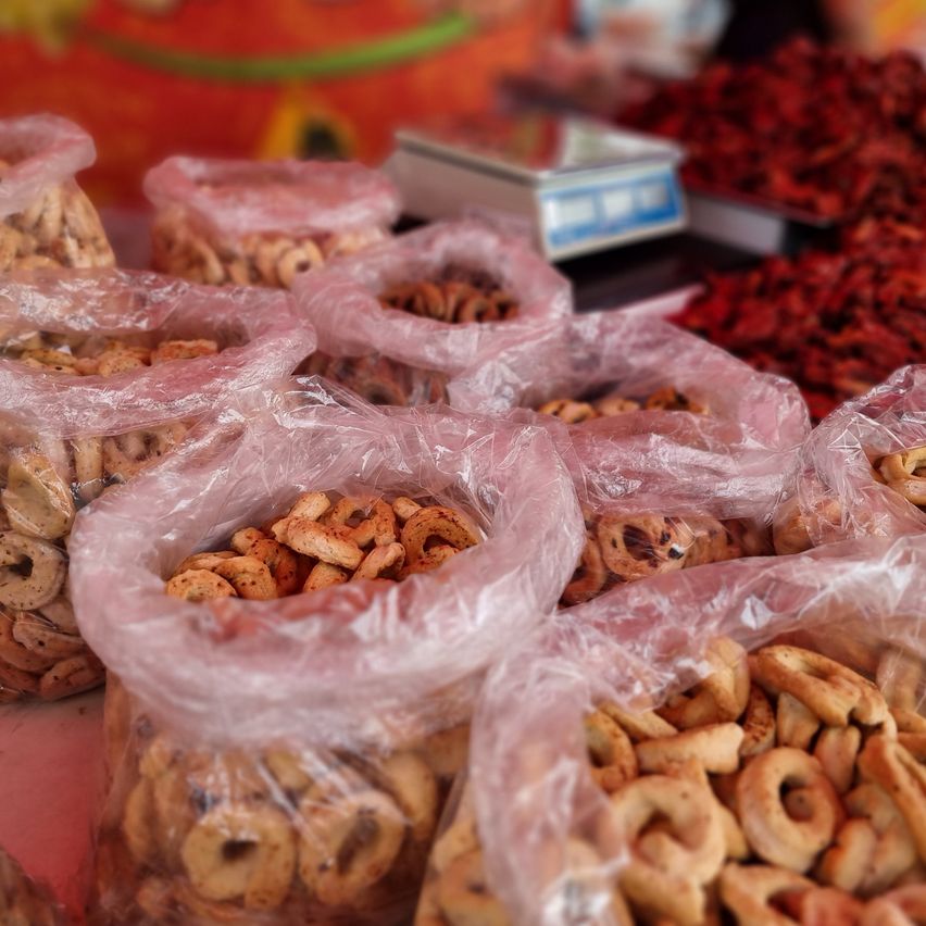 Mehrere Plastiktüten mit verschiedenen Arten von Keksen sind auf einem Tisch ausgestellt. Die Kekse haben unterschiedliche Formen und Größen und einige sind in Plastik eingewickelt.