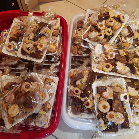 Zwei Tabletts gefüllt mit verschiedenen Arten von Keksen, jeder einzeln in Plastik verpackt. Die Kekse sind mit Sternen verziert und kommen in verschiedenen Formen und Geschmacksrichtungen.