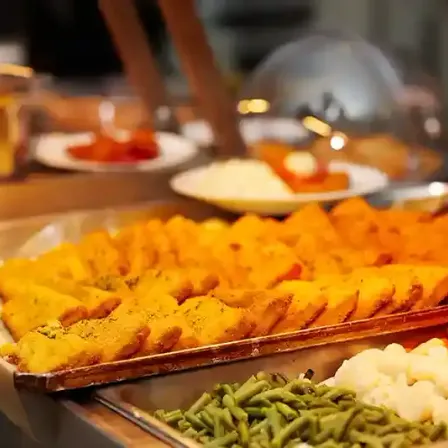 Ein Buffettisch bietet verschiedene Gerichte, darunter Maisbrot, grüne Bohnen und Kartoffelpüree.