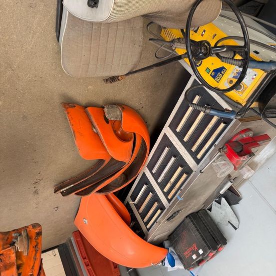 Ein Blick von oben auf eine Werkstatt mit einem orangefarbenen Kunststoffteil, einem Lenkrad und anderen Werkzeugen.