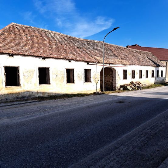 Eine leere Straße mit einem Gebäude mit einem braunen Dach und mehreren Fenstern an der Seite. Vor dem Gebäude steht eine Straßenlaterne.