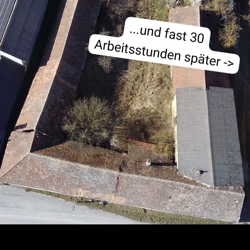 Luftaufnahme eines Gebäudes mit grauem Dach und Solarmodulen. Eine Notiz im Bild lautet '...und fast 30 Arbeitsstunden später >' und zeigt an, dass 30 Stunden Arbeit vergangen sind.