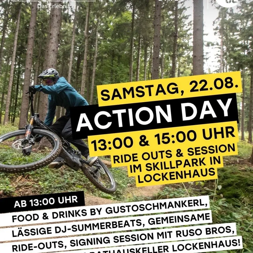 Ein Mann fährt ein Mountainbike im Wald, mit einem Schild, das einen Aktionstag am Samstag, 22. August um 13:00 Uhr und 15:00 Uhr ankündigt.