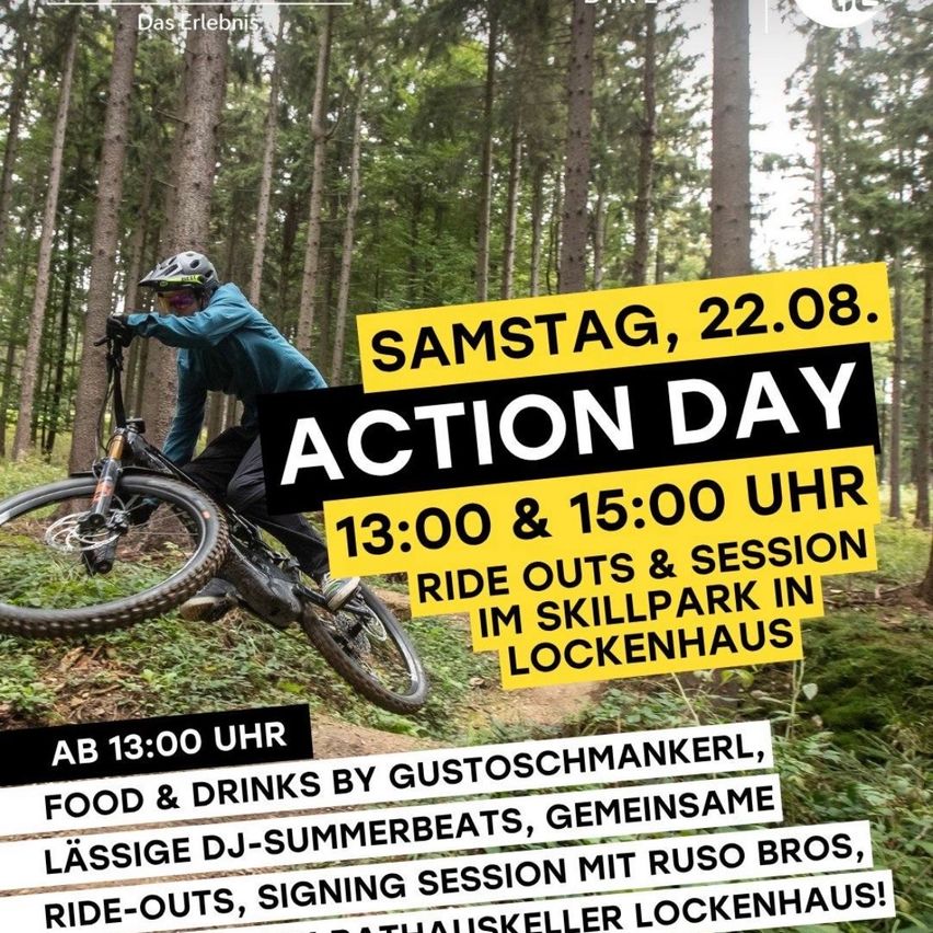 Ein Mann fährt ein Mountainbike im Wald, mit einem Schild, das einen Aktionstag am Samstag, 22. August um 13:00 Uhr und 15:00 Uhr ankündigt.