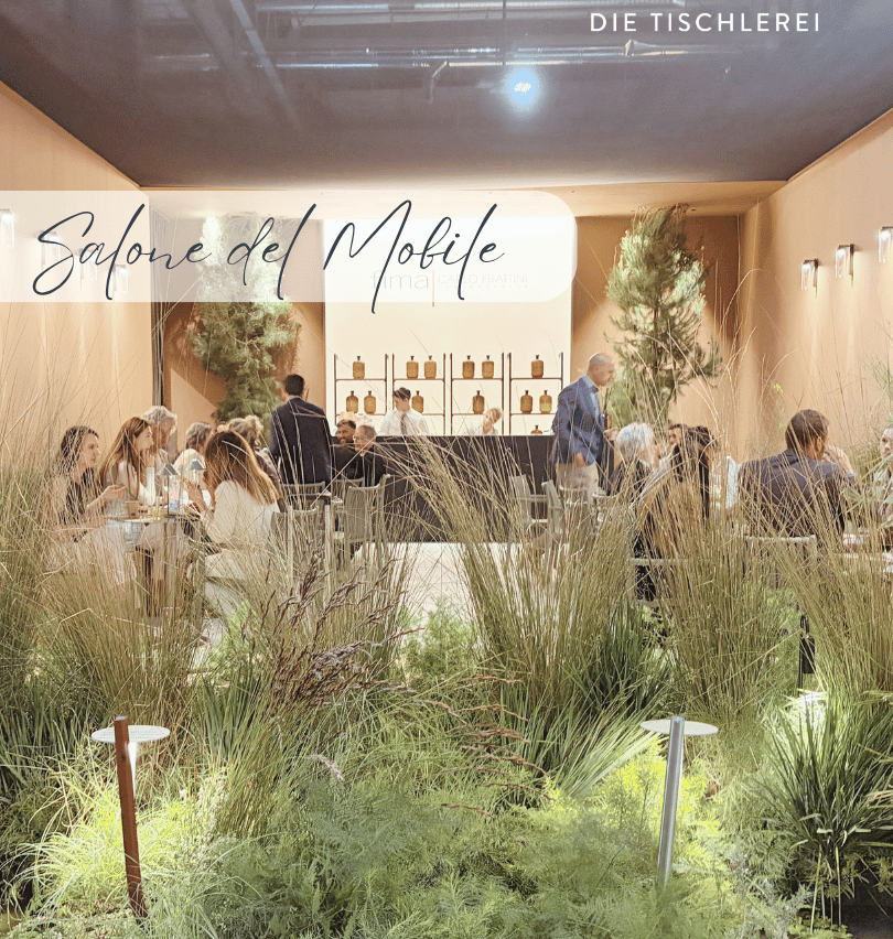 Ein Restaurant mit Gartenblick, Menschen sitzen an Tischen, einige stehen, es gibt Pflanzen und Lampen auf dem Boden.