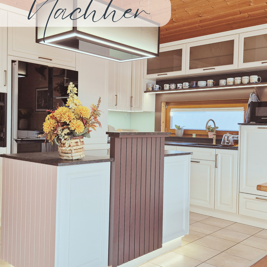 Eine moderne Küche mit Holzbalken an der Decke und einem Blumencenterpiece auf der Insel. Die Schränke und Arbeitsplatten sind weiß und der Boden ist gefliest.