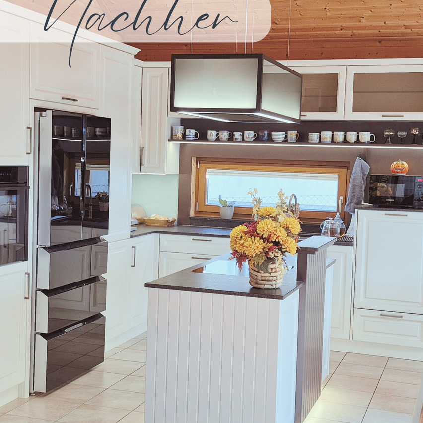 Eine Küche mit weißen Schränken, einer schwarzen Arbeitsplatte und einem Blumenarrangement. Eine Mikrowelle, eine Kürbis und ein Handtuch befinden sich rechts. Ein Kühlschrank und ein Ofen sind links.