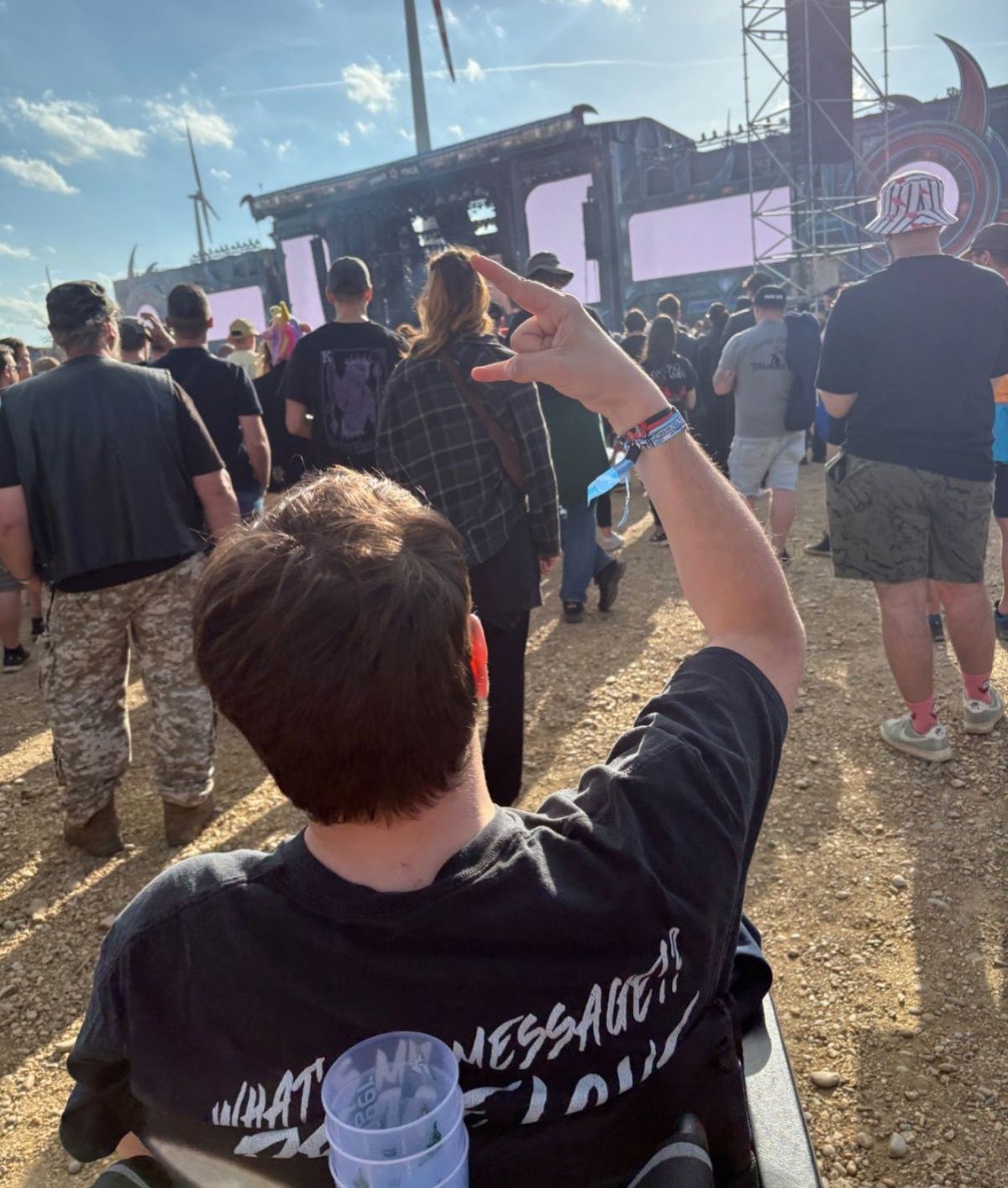 Ein Mann zeigt auf die Bühne bei einem Musikfestival, umgeben von einer Menschenmenge.