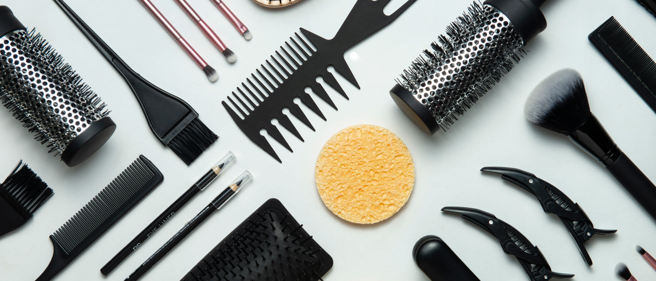 Verschiedene Haar- und Make-up-Utensilien, darunter Bürsten, Kämmen, Schwämme und andere Pflegeartikel, sind auf einem weißen Hintergrund ausgestellt.