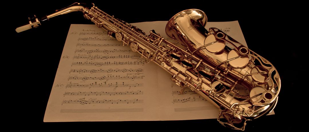 Ein goldenes Saxophon liegt auf einem Musikbogen. Das Saxophon hat eine glatte, polierte Oberfläche und komplizierte Designdetails. Der Musikbogen ist geöffnet, mit Noten und Symbolen in einem fließenden, komplexen Muster angeordnet.