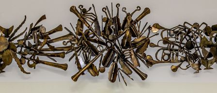 Drei junge Mädchen posieren mit Musikinstrumenten in einem Raum mit einem Kunstwerk an der Wand.