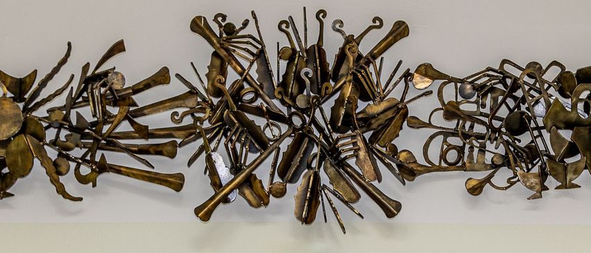 Drei junge Mädchen posieren mit Musikinstrumenten in einem Raum mit einem Kunstwerk an der Wand.