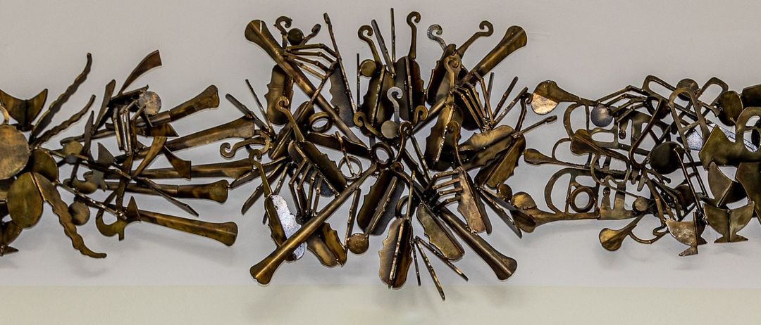 Drei junge Mädchen posieren mit Musikinstrumenten in einem Raum mit einem Kunstwerk an der Wand.