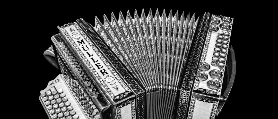 Ein Schwarz-Weiß-Bild eines Vintage-Akkordeons mit der Aufschrift Muller, mit komplizierten Designs und einer Tastatur.