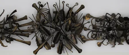 Eine Bronzeskulptur aus Musikinstrumenten, die in einem kreisförmigen Muster angeordnet sind. Verschiedene Instrumente wie Violinen, Trompeten und Celli sind kunstvoll verbunden. Eine Plakette am unteren Rand zeigt, dass sie von Wolfgang A. Hochinger stammt.