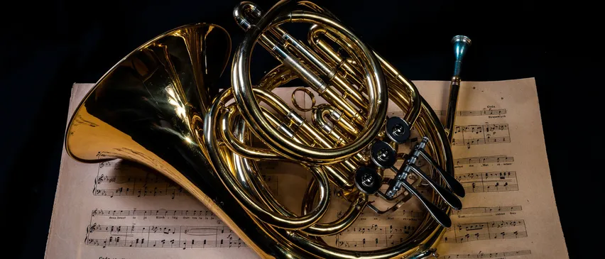 Ein goldenes Waldhorn liegt auf einem Musikblatt.