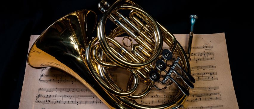 Ein goldenes Waldhorn liegt auf einem Musikblatt.