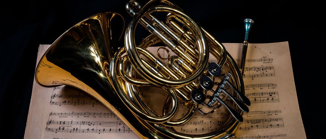 Ein goldenes Waldhorn liegt auf einem Musikblatt.