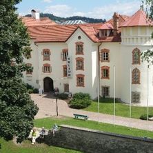 Ein Blick von oben auf ein großes weißes Gebäude mit rotem Dach, umgeben von Bäumen und Rasen.