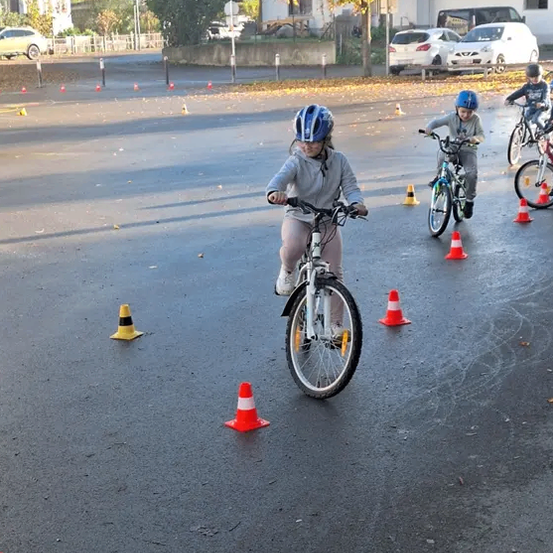 Kinder fahren auf einer Straße mit Verkehrskegel Helme und Turnschuhe tragen.