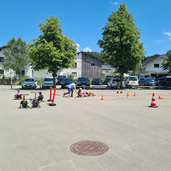 Eine Gruppe von Menschen nimmt an einem Rennen auf einem Betonfeld mit Verkehrskegeln teil. Eine Person beugt sich vor.