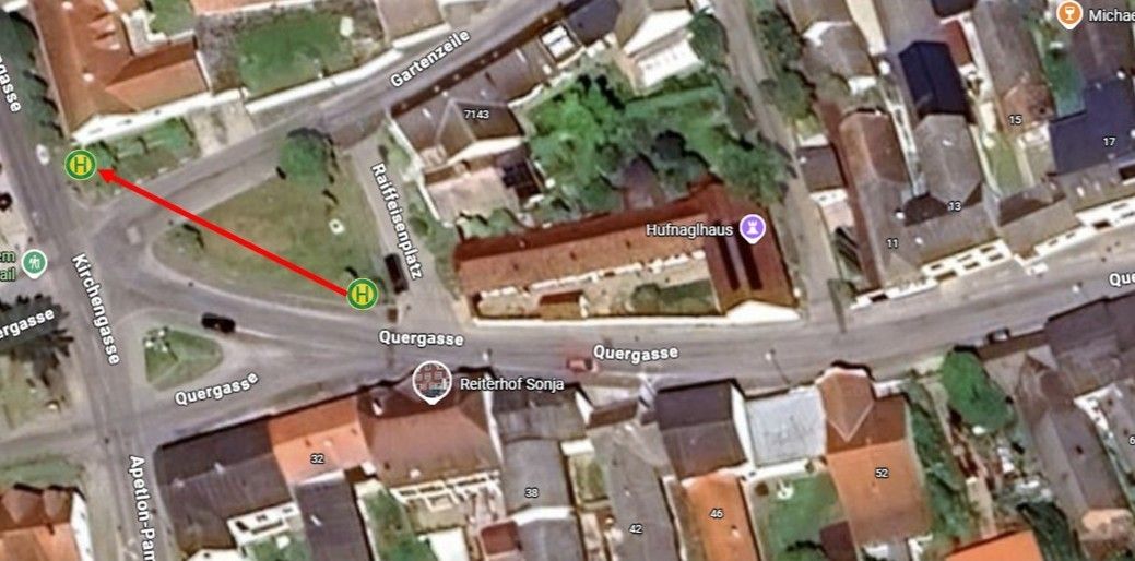 Eine Karte zeigt ein Wohngebiet mit Gebäuden, Straßen und einem markierten Ort. Die Quergasse kreuzt die Raffeisenplatz-Straße. Ein roter Pfeil zeigt auf einen markierten Bereich.