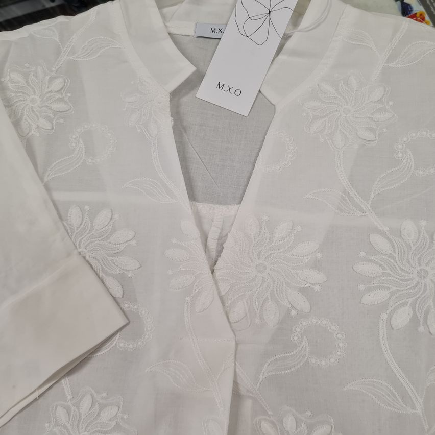 Eine weiße Bluse mit kunstvollen Blumenstickereien auf durchsichtigem Stoff, Größe M. Der angebrachte Tag lautet MXO.