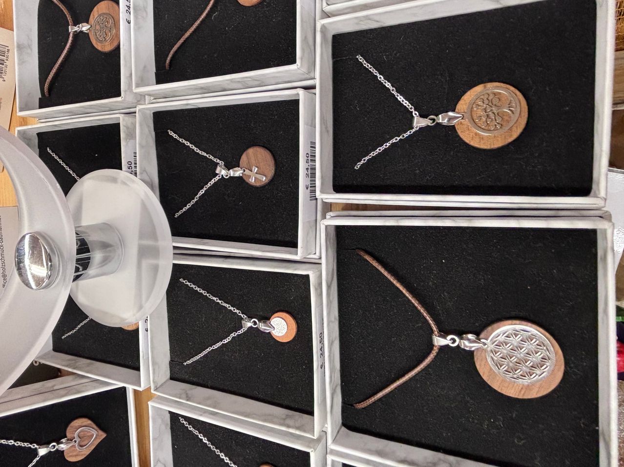 Eine Sammlung von Halsketten in Marmor- und Holzboxen mit silbernen Ketten und Anhängern in verschiedenen Designs, einschließlich Kreuz- und Blumenmustern.