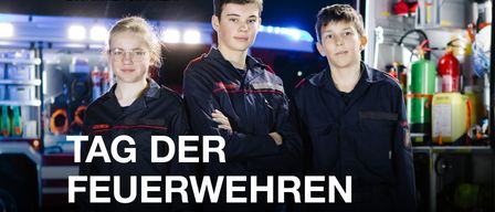 Drei junge Leute in Uniform stehen neben einem Feuerwehrwagen. Sie sehen ernst aus. Der Text lautet 'G DER UERWEHREN'.