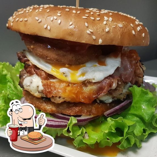 Ein großer Hamburger mit Sesambrötchen, belegt mit gebratenem Ei, Speck, Käse und Salat. Ein gezeichneter Mann hält ein Getränk und gibt Daumen hoch.