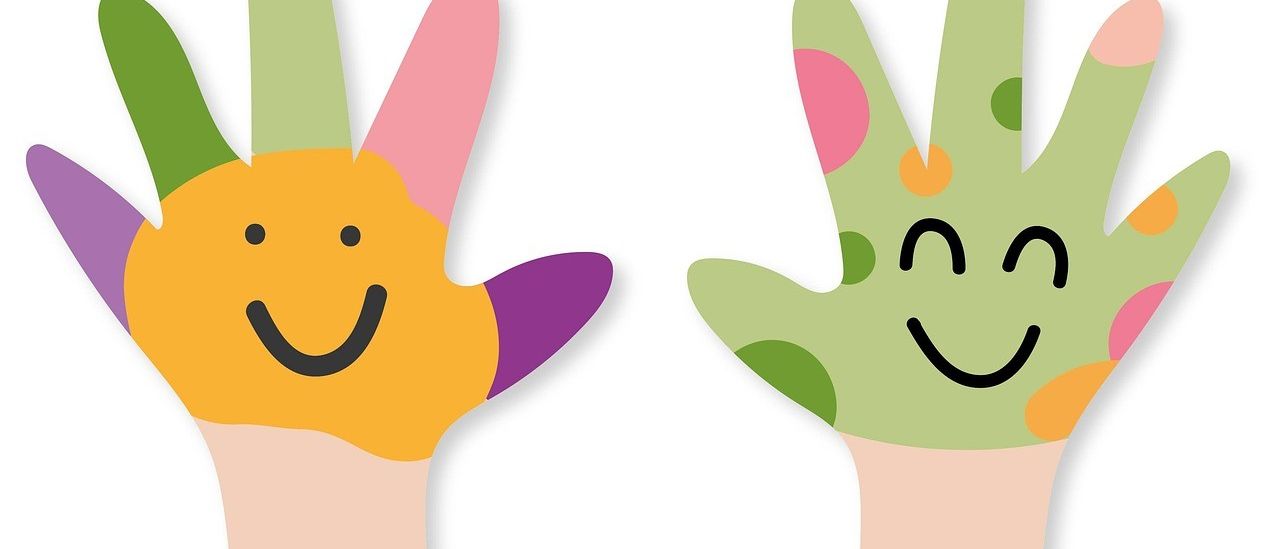 Zwei Hände, eine gelb und eine grün, sind gegen einen weißen Hintergrund erhoben. Jede Hand hat ein lächelndes Gesicht mit unterschiedlichen Merkmalen und farbigen Punkten an den Fingern.