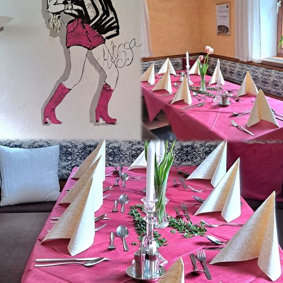 Ein Essbereich mit rosa Tischdecke, gefalteten Servietten und Besteck. An der Wand befindet sich eine Zeichnung einer Frau in Stiefeln.