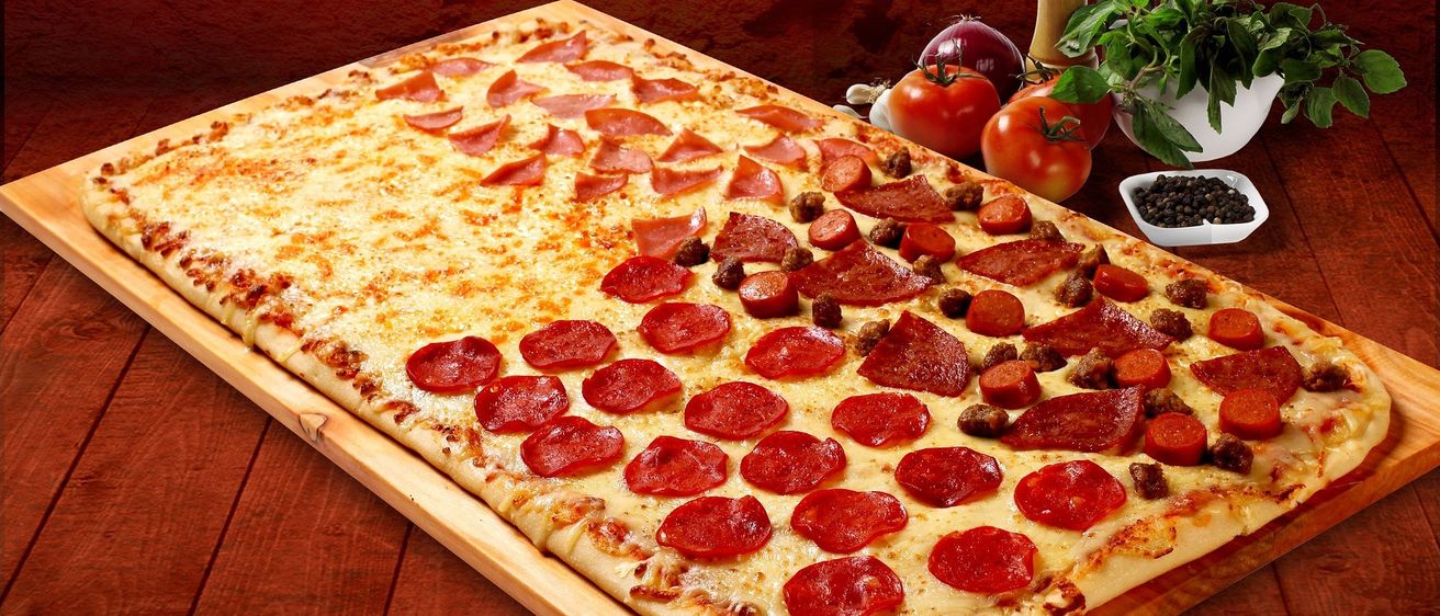 Eine große Pizza mit Pepperoni, Wurst und Pepperoni-Toppings auf einem Holzbrett mit rotem Hintergrund.