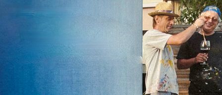 Ein blaues Poster zeigt 'DUO in ACRYL' mit den Namen 'Krebsler & Plutzer'. Zwei Männer in bemalter Kleidung, einer mit einem Weinglas, stehen auf einem Rasen.