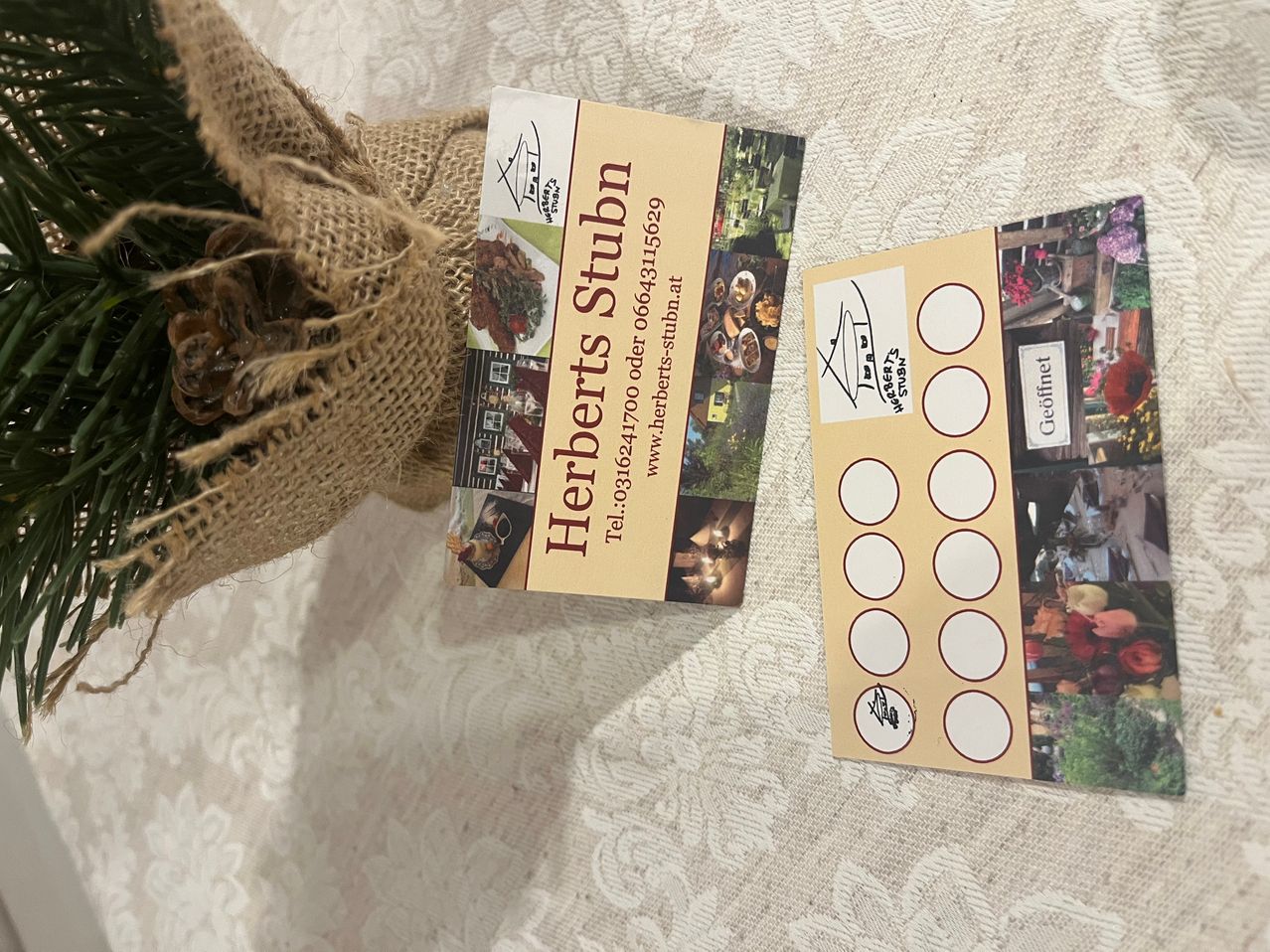 Eine Visitenkarte von Herberts Stuben zeigt mehrere Bilder von Speisen und Getränken. Daneben befindet sich eine Werbekarte für Geofinel mit mehreren Kreisen.