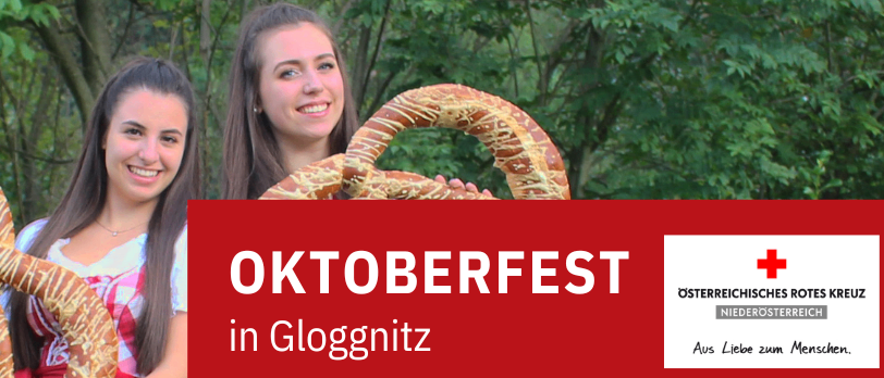 Zwei lächelnde Frauen halten eine Brezel vor einem herzförmigen Banner. Darunter steht 'Oktoberfest in Gloggnitz'.