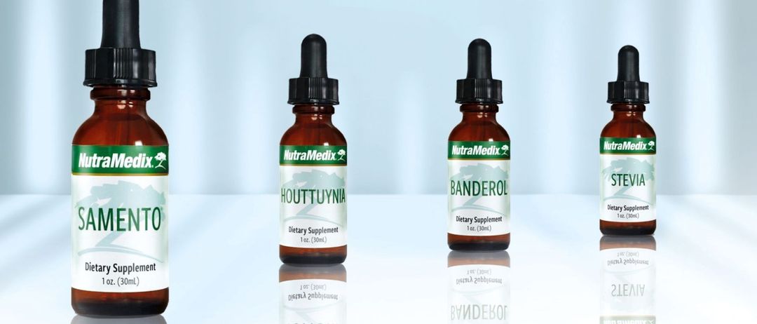 Zwei braune Flaschen mit schwarzen Kappen stehen auf einer weißen Oberfläche. Eine Flasche hat das Etikett 'HOUTTUYNIA' und die andere 'BANDEROL'. Beide sind als Nahrungsergänzungsmittel gekennzeichnet.