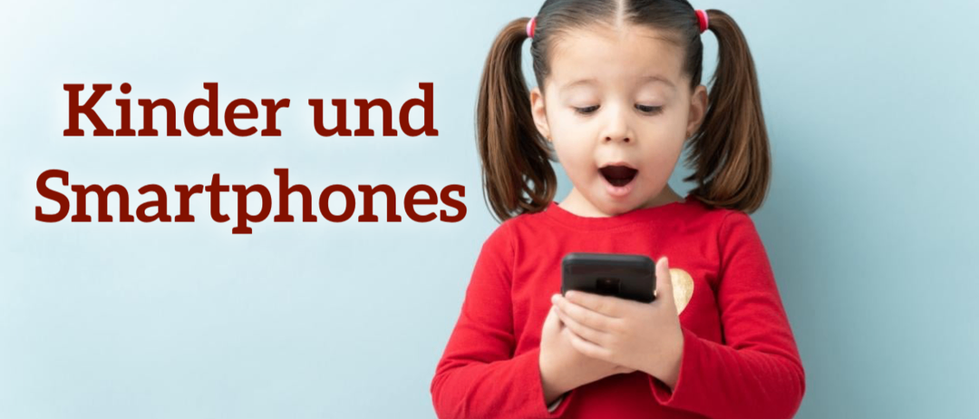 Ein kleines Mädchen mit Zöpfen schaut mit offenem Mund auf ihr Smartphone.