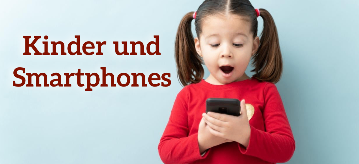 Ein kleines Mädchen mit Zöpfen schaut mit offenem Mund auf ihr Smartphone.