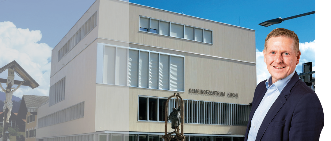 Das Bild zeigt eine Anzeige für eine Gemeindeversammlung. Die Veranstaltung trägt den Titel 'Bürgerversammlung 2026' und beginnt um 19:00 Uhr. Der Ort ist Pfarrsaal. Ein Mann ist vor einem modernen Gebäude abgebildet, möglicherweise dem Veranstaltungsort.