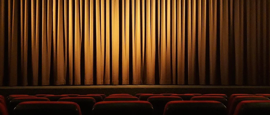 Ein leeres Theater mit roten Sitzen und einem Vorhang.