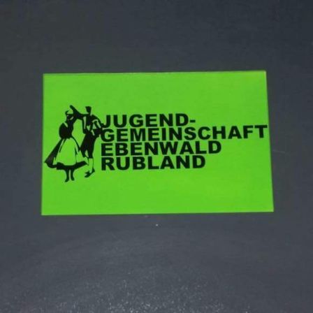 Ein neongrüner Aufkleber mit zwei tanzenden Figuren. Der Text lautet 'Jugend-Gemeinde Ebenwald Rubland'.